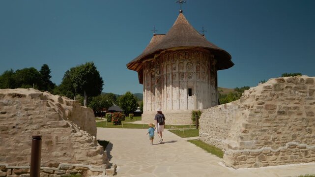A young mother and her little boy walk near Humor Monastery. They explore the grounds and look at the building and surroundings during a sunny day.