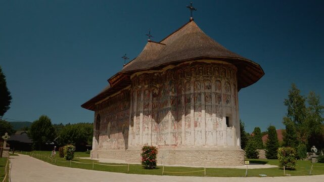 A young mother walks with her little boy at Humor Monastery. They explore the grounds and admire the colorful paintings on the walls during their visit.