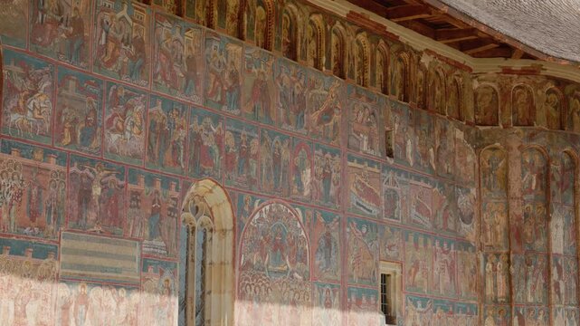 Visitors see the wall paintings at Humor Monastery located in Bucovina Romania. This site showcases unique art and architecture from the past.