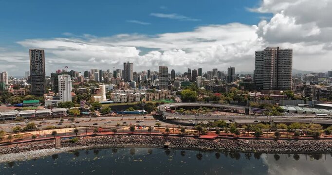 Beautiful aerial view of Mumbai city skyline along the Arabian Sea, featuring modern high-rise buildings, sandy beaches, and a vibrant coastal landscape under a bright blue sky.