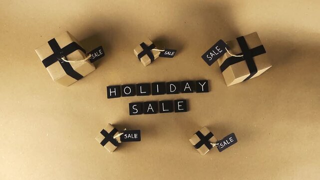Creative top down view of the text holiday sale surrounded by little gift boxes with black ribbon and tags. Commercial concept for shopping, discounts, and seasonal promotions like Black Friday