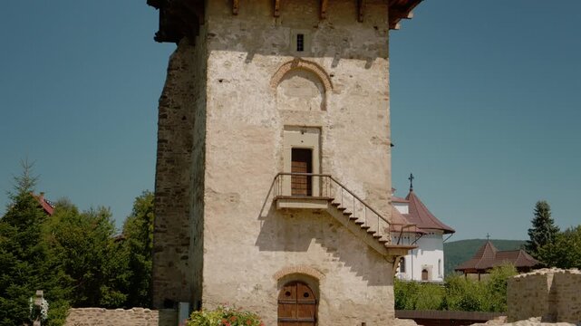 Explore Humor monastery in Bukovina with its ancient walls and tower. Discover the history and art of old paintings in a peaceful setting during the day.