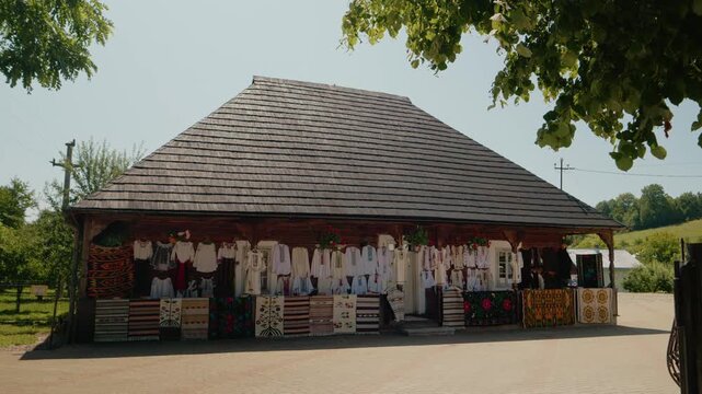 Traditional Bucovinian house shows Romanian national costumes on display. Visitors see handmade garments and crafts in this cultural setting during the day.
