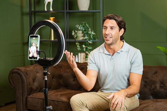 Man creating content on social media, livestreaming with a ring light and phone