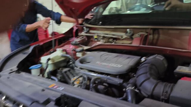 Mechanic removes damaged front windshield from car at automotive repair garage. Footage shows windshield replacement and auto glass repair process, highlighting vehicle maintenance