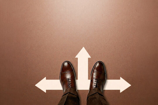 Businessman standing before three directional arrows making career decision at crossroads