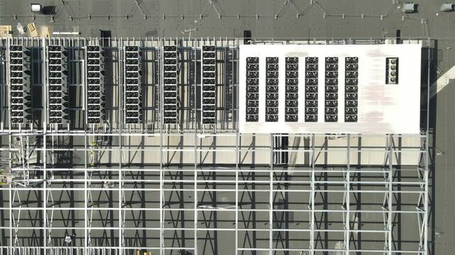 Overhead perspective showing the industrial cooling systems and ventilation fans on the rooftop of a large data center, with a new section of structural steel framing under construction