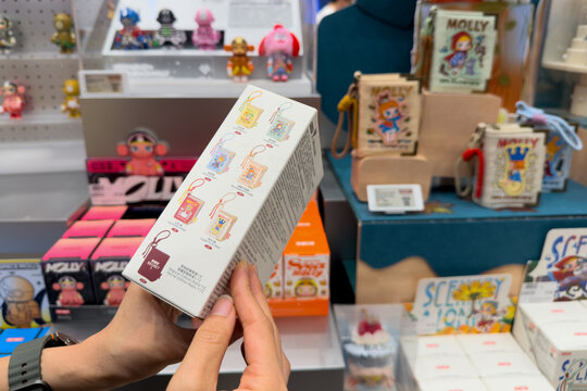 PENANG, MALAYSIA - JUL 03, 2026: Hand holding Pop Mart Molly 20 Years mini memory album bag blind box inside retail toy store.