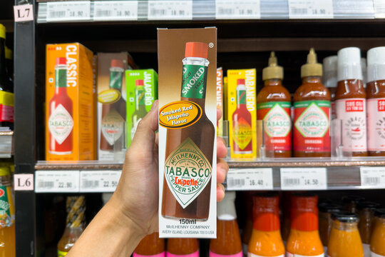 PENANG, MALAYSIA - JUL 03, 2026: Hand holding Tabasco Chipotle pepper sauce box inside supermarket grocery store.