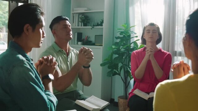 Top view of skilled diverse prayer clasping hand and praying to god while sitting at chair in circle. Top down aerial view of people folded hand while sitting with opened bible on laps. Symposium.
