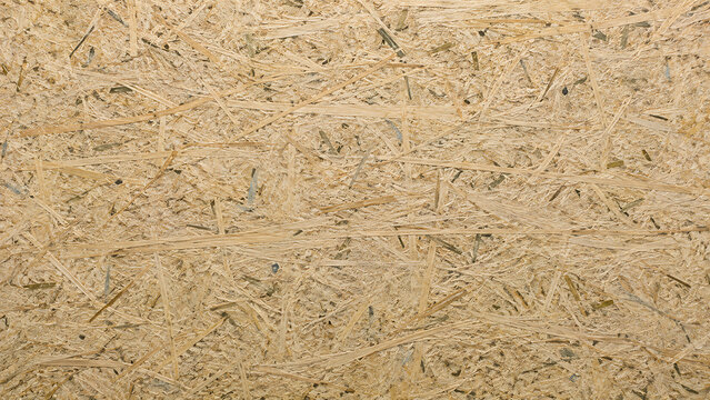 Close-up view of a textured wooden surface, possibly oriented strand board or particle board, showing interwoven wood strands and fibers.