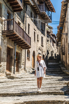 Woman in white dress standing on medieval stone street in Rupit village, Catalonia, Spain