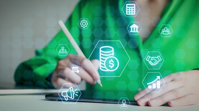A person is using a stylus on a tablet with financial icons around them. This scene takes place in an office setting during the day. The focus is on digital interaction with finance.