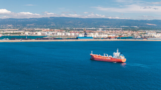 Aerial view of oil tanker sailing near industrial port and refinery facilities on Mediterranean coast in Tarragona Spain