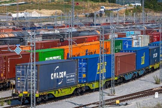 Koper, Slovenia - August 07, 2026: Vast railway freight yard at a port terminal with cargo containers, tank cars, and autorack train cars.