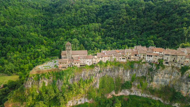 Aerial drone view of Castellfollit de la Roca medieval village perched on dramatic basalt cliff in Catalonia Spain
