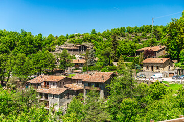 Fototapeta premium Panoramic view of traditional stone houses surrounded by lush green forest in Rupit village, Catalonia, Spain