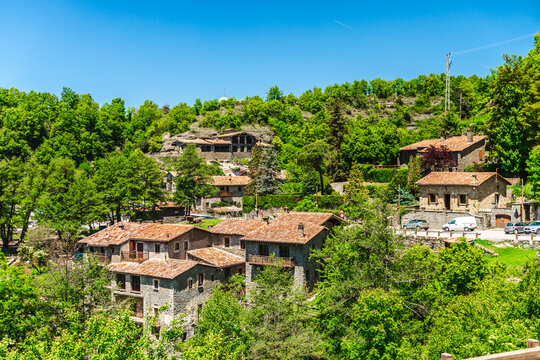 Panoramic view of traditional stone houses surrounded by lush green forest in Rupit village, Catalonia, Spain