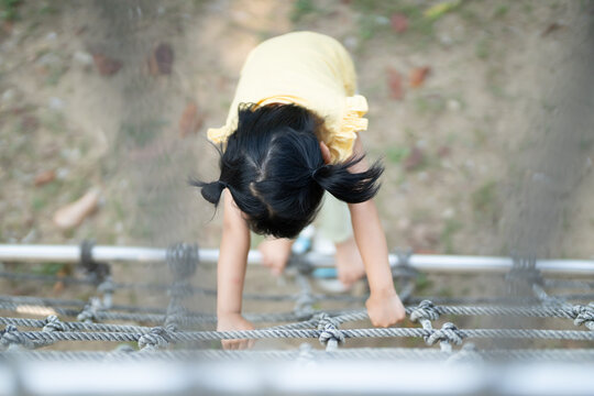 child climbs up an alpine grid in a park on a playground on summer day. children playground in a public park, entertainment and recreation for children, holiday, IQ, EQ, Relax, Development