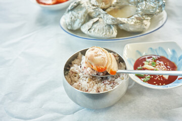 A close up macro of traditional Asian seafood dining featuring fresh hard clams and mixed grain rice. Foil wrapped steamed shells and vibrant side dishes highlight authentic regional coastal gastronom © 진영김