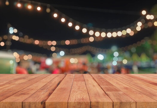 Empty wooden table top with blurred festive bokeh lights at night market