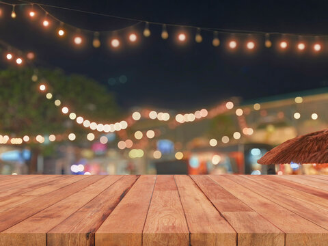 Empty wooden table top with blurred festive bokeh lights at night market