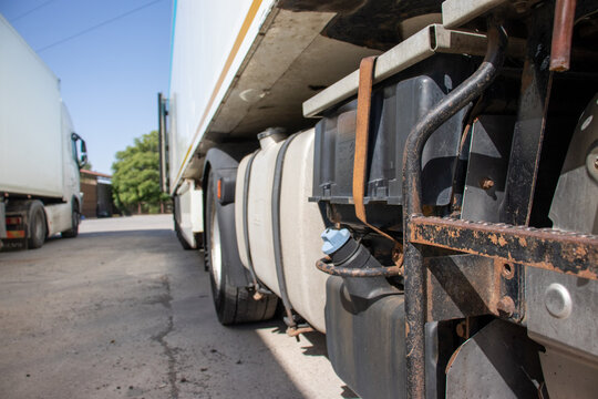 Side view of a semi-truck showing the fuel tank, AdBlue tank, and chassis equipment parked outdoors. Concept of commercial transport, freight logistics, and long-haul vehicle maintenance.