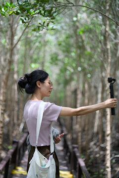 Woman vlogger filming a mangrove forest with a handheld gimbal camera