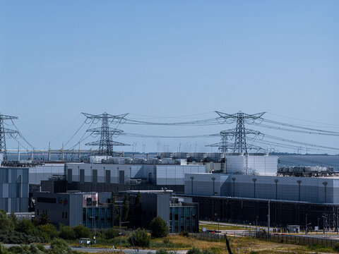 Eemshaven, Netherlands - 13 August 2026: Aerial view of the Google data center facility with large industrial buildings, power lines, and wind turbines.