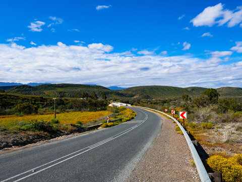 Scenic view of the R62 winding through the Little Karoo and crossing the Groot River near Ladismith in the Western Cape, South Africa, a spectacular route through rugged mountains and arid scenery.