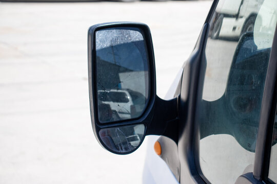Close-up of a commercial vehicle side mirror with an additional blind spot mirror segment. Concept of road safety, driver vision, transport equipment, and logistics safety.