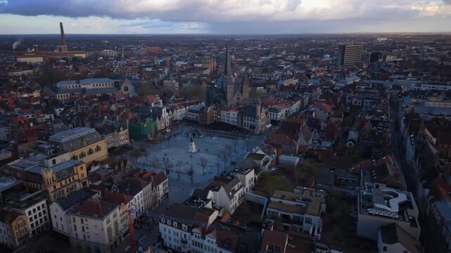 Cinematic aerial Ghent Belgium captures stunning drone view of historic city center with medieval church spires and traditional Flemish architecture. Dramatic cloudy sky frames the urban landscape.