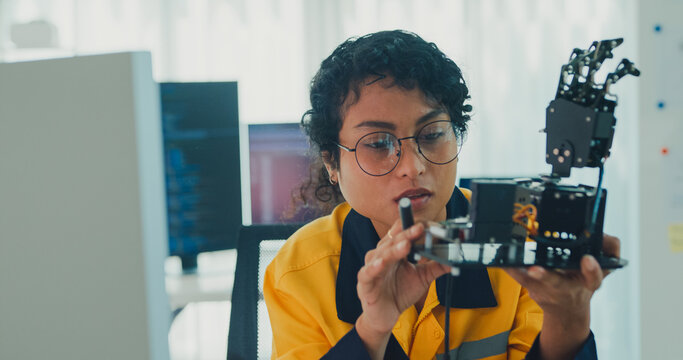 Young Black female engineer coding AI robot arm in modern laboratory. Robotics, artificial intelligence, technology, stem, future, innovation, diversity, automation, machine learning concept.