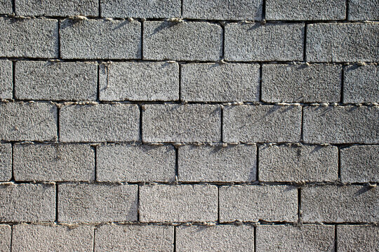 Seamless grey cinder block wall texture with visible mortar lines. Rough concrete masonry background concept for construction, architecture, and building design.