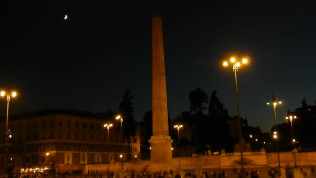 Night panorama with dark sky, moon, Flaminio Obelisk, lantern lights in Piazza del Popolo an tourist traffic in Rome in Italy. Topics: capital, city center, travel, tourism, Europe