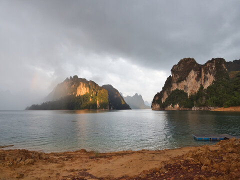Ratchaprapha Dam in the morning featuring sunlight and mist amidst khao sok national park in surat thani province thailand where towering limestone cliffs rise from the freshwater reservoir.