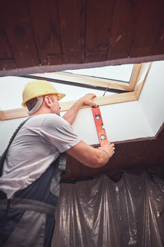 Carpenter installing roof windows in the attic.