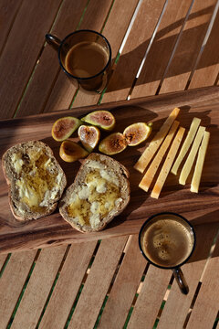 Romantic Mediterranean summer breakfast with figs, cheese and honey served outside with coffee on a wooden board