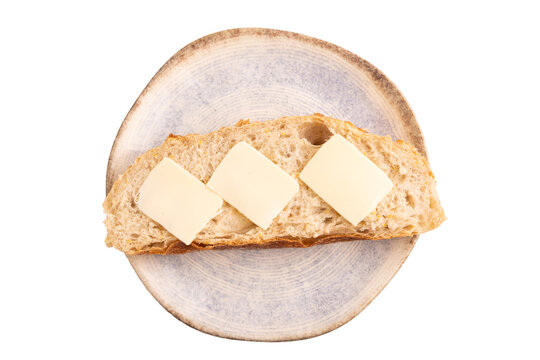 Slice of homemade bread with butter on blue plate isolated on white, close up, top view.