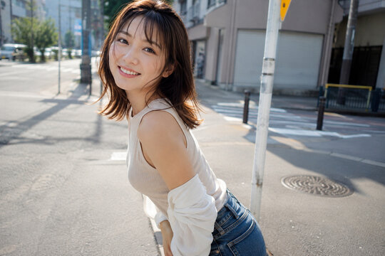白いタンクトップとシャツで街角を歩く女性