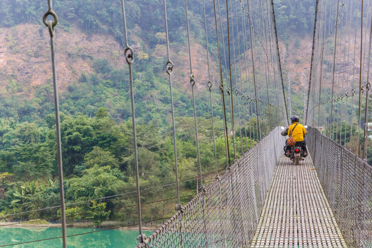 Motorcycle crossing suspension bridge over the Trishuli river in Nepal