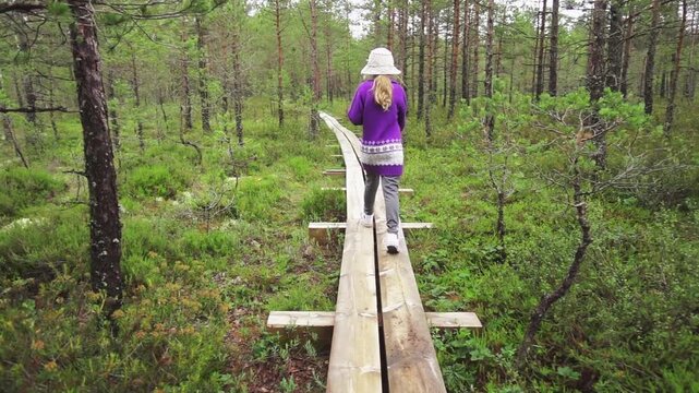 Little beautiful girl walks on swamp in Estonia