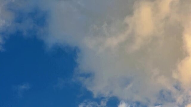 Fluffy yellow clouds on blue sky background time lapse