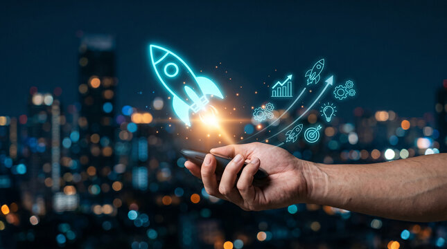 Hand holding phone with neon rocket and business icons, symbolizing startup, growth, and digital innovation against blurred city lights
