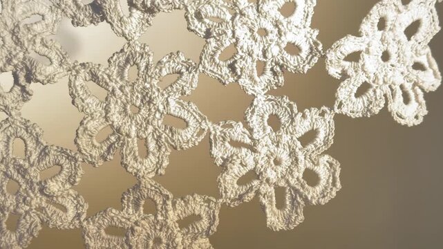 Handmade white crochet lace flowers with sweeping light on a static beige background for craft design and artisan visuals