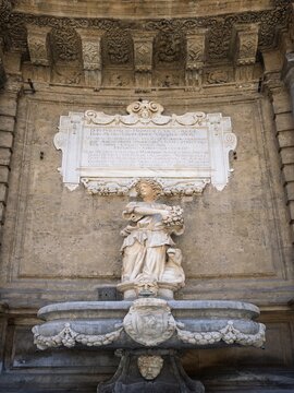 Intricate Baroque fountain depicting Spring at Quattro Canti in Palermo, showcasing a carved marble goddess holding flowers beneath an engraved Latin commemorative tablet.