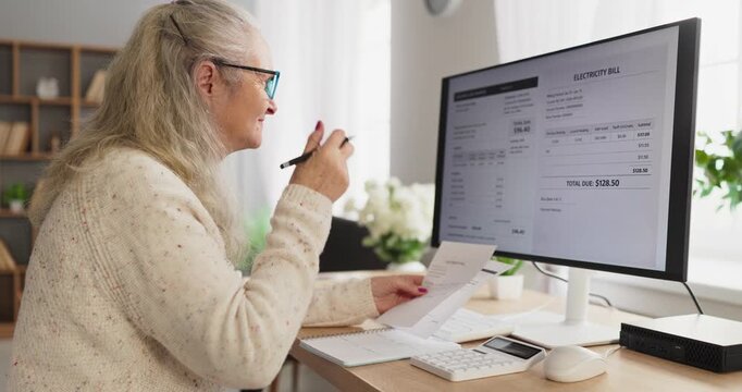 Senior woman checks electricity bill on computer. At home she reviews budget and expenses, plans online payment, and tracks finance with a calculator. Clear view of household utility costs.