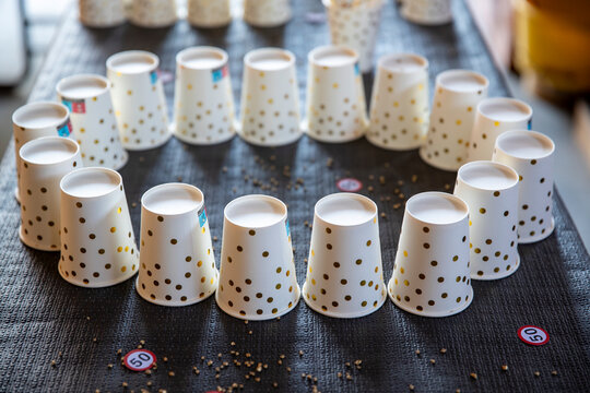 Des gobelets jetables en papier blancs &agrave; pois dor&eacute;s dispos&eacute;s en cercle sur une table, accompagn&eacute;s de petits &eacute;l&eacute;ments d&eacute;coratifs avec num&eacute;ros.