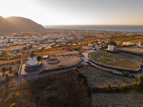High aerial drone panorama of whitewashed windmills on Gavrilos Hill above Emporio in Santorini Greece