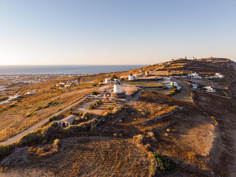 Scenic aerial drone view of the row of historic windmills along Gavrilos Hill ridge near Emporio Santorini